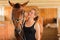 Jockey young girl petting and hugging brown horse