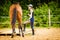 Jockey young woman getting horse ready for ride