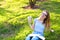 Jocund female freelancer sitting on green grass with documents in park and keeping money.