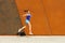 Jogger woman jump by the wall in city.