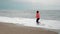 Jogging on beach. Woman runs on sea waves. Running woman on seashore. Motivated sporty female is running at shoreline, waves splas