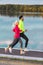 Jogging Ideas. Running Couple While Training Outdoors on Road At River For Durable Marathon Pretty Young Female and Extremely Fit
