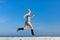 Jogging. Young sportswoman in blue sportswear runs along seafront