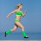 Jogging. Young sportswoman in green sportswear running