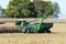 John Deer 8400 tractor pulling a Brent 1196 grain cart while loading corn from a harvester