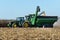 John Deer 8400 tractor pulling a Brent 1196 grain cart while loading corn from a harvester