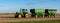 A John Deere farm tractor parked in a field with a couple grain hopper trailers attached