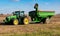 A John Deere farm tractor parked in a soybean field