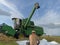 John Deere harvester works in the field. Combine Harvesting Wheat