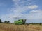 John Deere harvester works in the field. Combine Harvesting Wheat