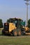 John Deere road grader in a field with green grass and blue sky in Kansas.