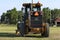 John Deere road grader in a field with green grass and blue sky in Kansas.