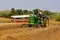 John Dere tractor and swather harvesting wheat