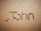 A John name written on the beach.
