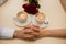 joined hands on a table with two cups of cappuccino with a bouquet roses