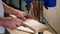 joiner is installing furniture loop in wooden detail, working in his workshop, closeup of hands