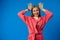 Joking young woman making horns with fingers over blue background