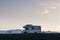 JOKULSARLON, ICELAND - AUGUST 2018: Campervan parked at black beach at sunset with snow capped glacier in the background