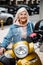 Jolly elderly female with motorbike stock photo