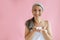 Jouful silver haired Asian lady with handful of foam stands on pink background