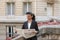 Journalist reading newspaper near high building.