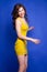 Jovial young model posing in yellow dress on blue background