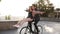Joy and happiness of young couple have fun riding on the same bike in outdoor activity with sun backlight on the