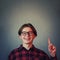 Joyful adolescent guy gesturing, pointing index finger up , happy expression isolated on grey wall background with copy space.