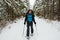 Joyful adventurer, with big backpack, is walking in snowshoes