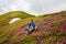 Joyful adventurer relaxes among flowering pink rhododendrons