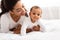 Joyful African Mommy Playing With Toddler Baby On Bed Indoor