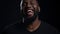 Joyful afro guy laughing in studio. African american man making gestures indoors