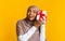 Joyful afro muslim woman holding present, shaking box, guessing what`s inside