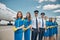 Joyful airline workers or aircrew standing outdoors in airfield