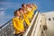 Joyful airline workers standing on airplane stairs under blue sky