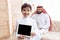 Joyful Arab boy looks at computer tablet while father works.