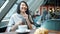 Joyful Asian lady using smartphone touching screen smiling and laughing at table in cafe