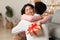 Joyful Asian Wife Embracing Husband Receiving Christmas Gift At Home