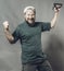 Joyful bearded craftsman in green t-shirt having fun with staple gun