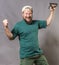 Joyful bearded craftsman in green t-shirt having fun with staple gun