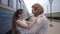 Joyful beautiful girl hugs boyfriend and laughs near train wagon on railway platform after separation