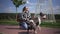 Joyful beautiful young woman supporting dog catching ball in city park outdoors. Portrait of cheerful confident