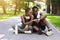 Joyful black couple resting after jogging in park, checking smartwatch