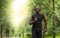 Joyful black guy jogging by summer forest