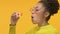 Joyful black woman blowing soap bubbles on yellow background, youth happiness