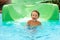 Joyful boy descends from the water slide in the water park, children& x27;s attractions in the water park, water