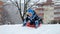 Joyful boy gliding down a snowy hill on plastic sleds, captured in slow motion for added emphasis on the fun and excitement of the