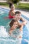 Joyful boy and parents in water of outdoor pool