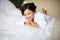 Joyful bride in the morning on the bed in bathrobe smiling cheerful, positive, with a ready hairdo and make-up, a