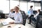 Joyful businesswoman in formalwear working on laptop in the modern office with collegues on the background